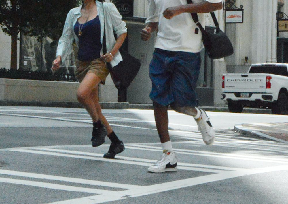 Two friends running across a crosswalk, Bottle Bag swinging at their sides