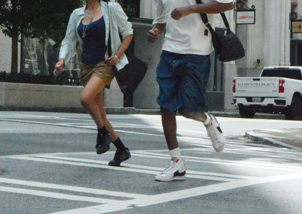 Two friends running across a crosswalk, Bottle Bag swinging at their sides